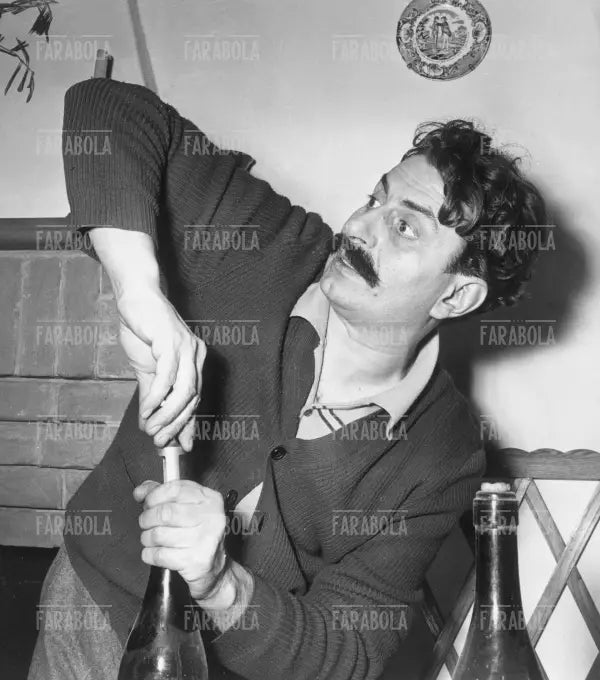 Giovanni Guareschi apre bottiglie di vino nella sua cantina, 1950