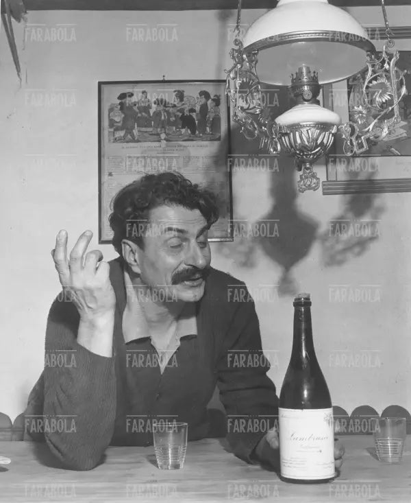 Giovanni Guareschi apre bottiglie di vino nella sua cantina, 1950