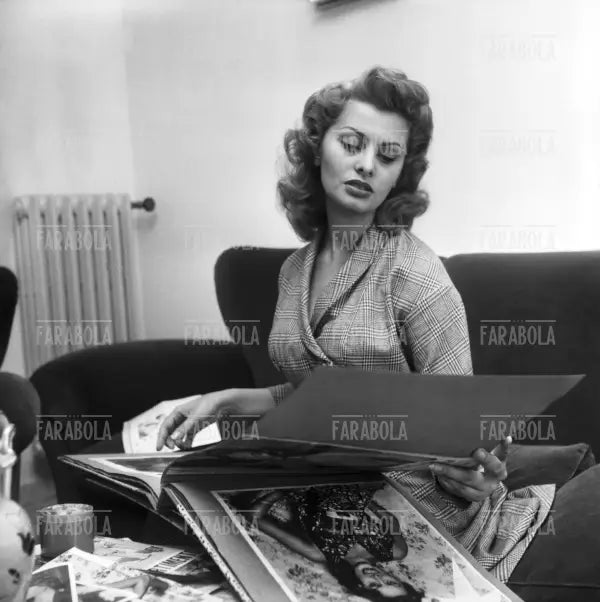 Sophia Loren sfoglia un album di fotografie a casa, Roma, 1954