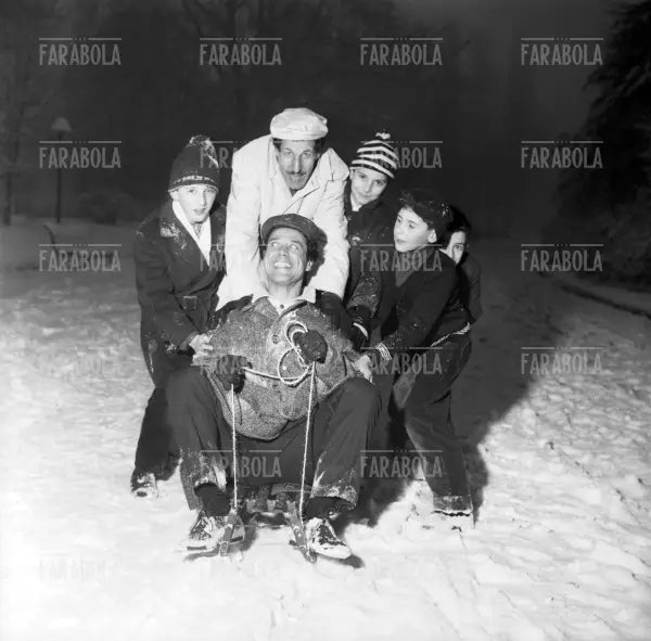Franco Franchi e Ciccio Ingrassia con lo slittino e alcuni bambini al parco, Milano, 1963