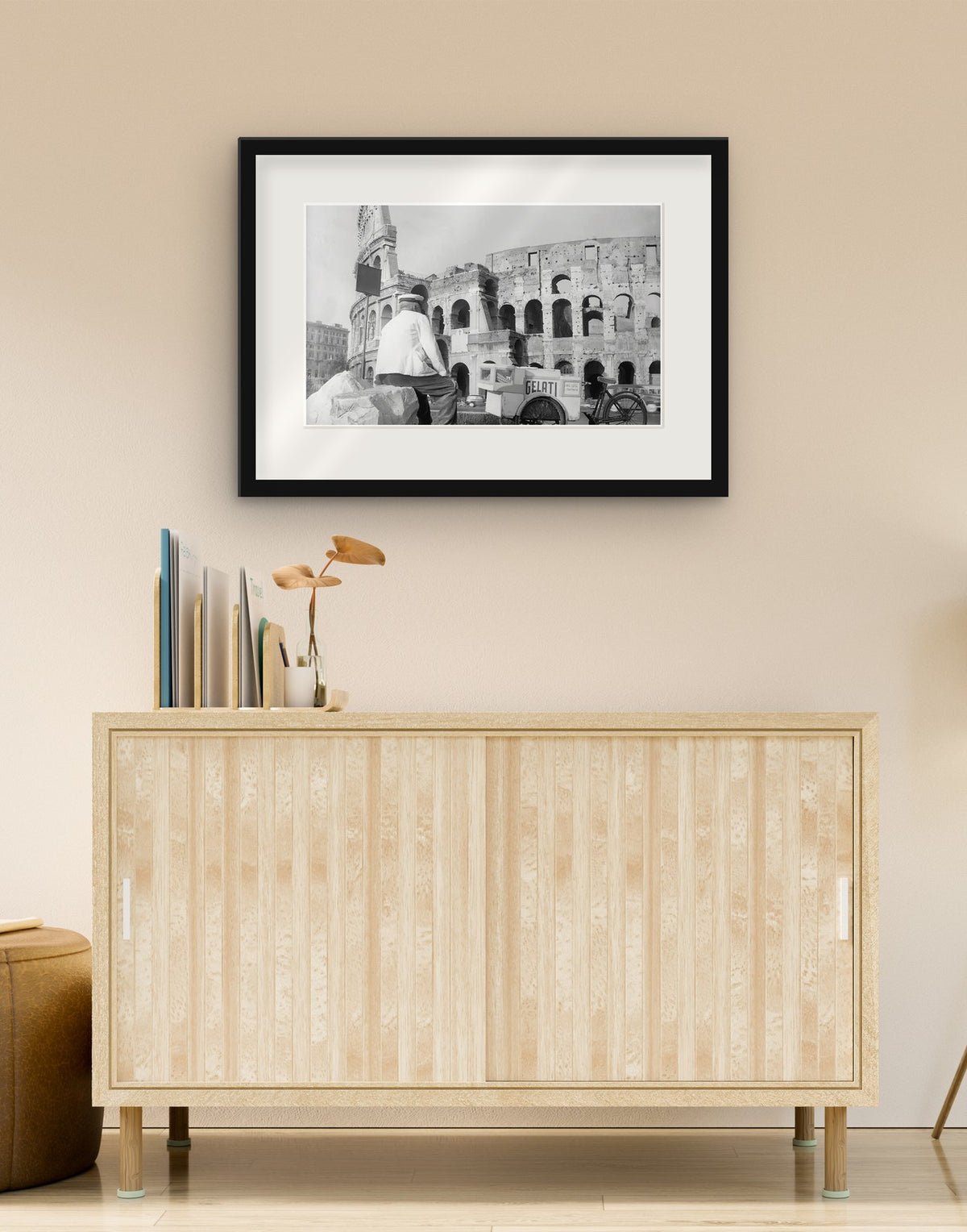 Stampa fine art di «Gelataio al Colosseo, Roma 1954» con cornice nera e passepartout, appesa in un soggiorno sopra una credenza