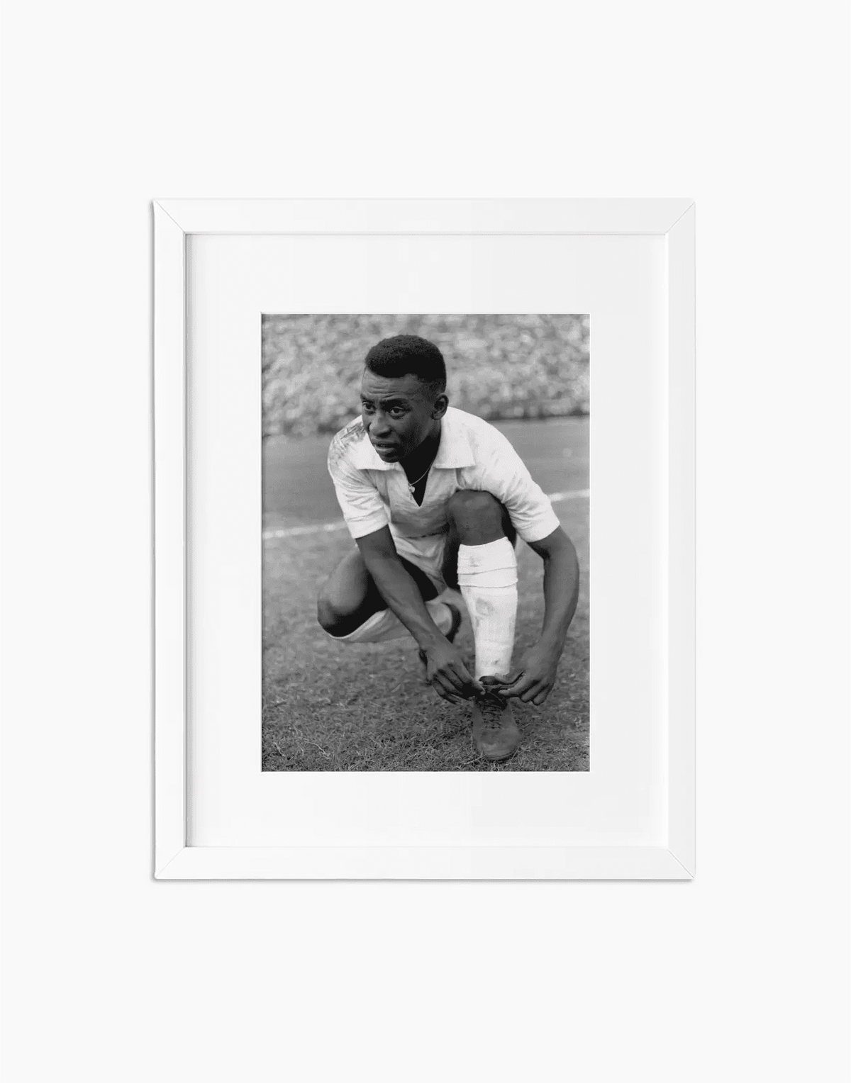 Pelè si allaccia le scarpe, Santos 1964 — stampa fine art con cornice bianca