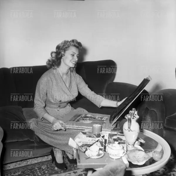 Sophia Loren sfoglia un album di fotografie a casa, Roma, 1954