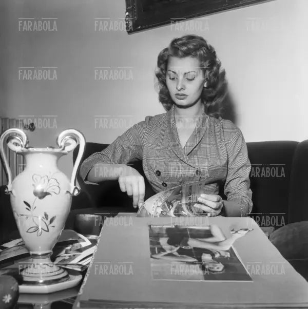 Sophia Loren sfoglia un album di fotografie a casa, Roma, 1954