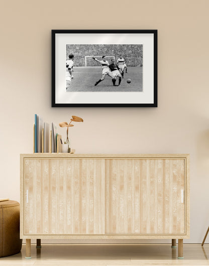 Tirage d'art de « Duel Liedholm-Randon, AC Milan-Bologna 1955 » avec cadre noir et passe-partout, accroché dans un salon au-dessus d'un buffet