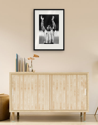 Fine-Art-Druck von „Diego Armando Maradona, WM Italia '90“ mit schwarzem Rahmen und Passepartout, im Wohnzimmer über einer Anrichte aufgehängt