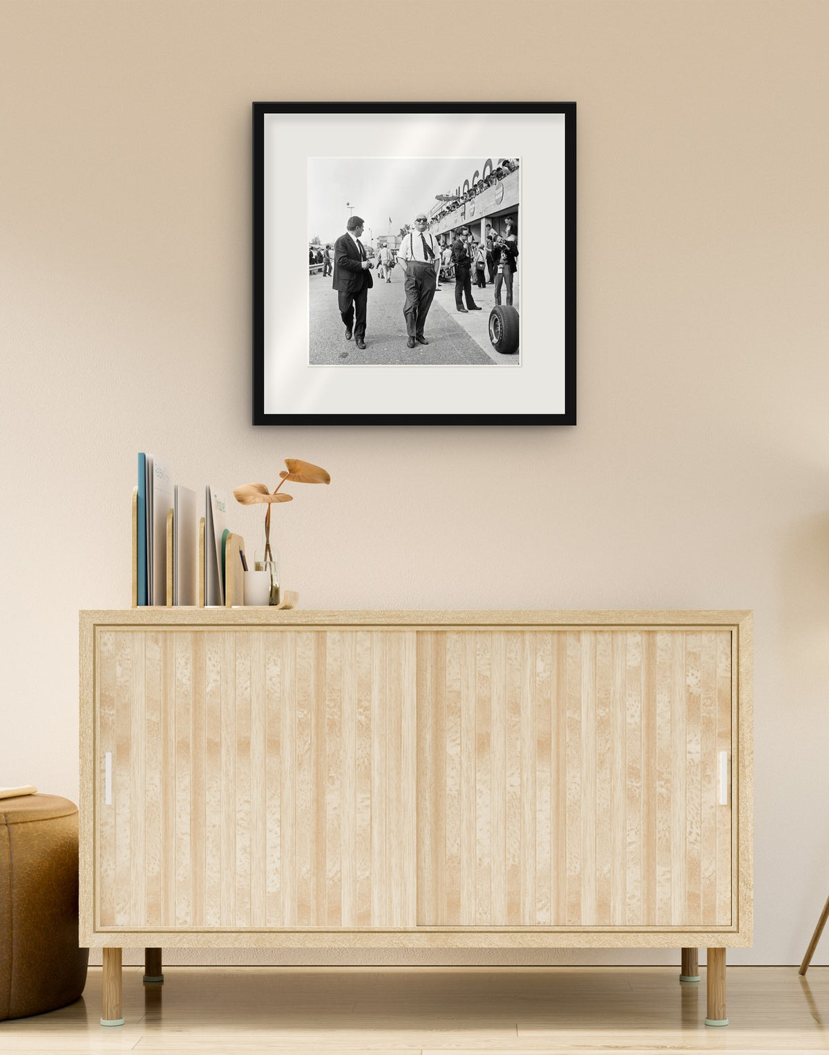 Fine art print of “Enzo Ferrari, Italian Grand Prix 1966” with black frame and mat, hanging in a living room above a sideboard