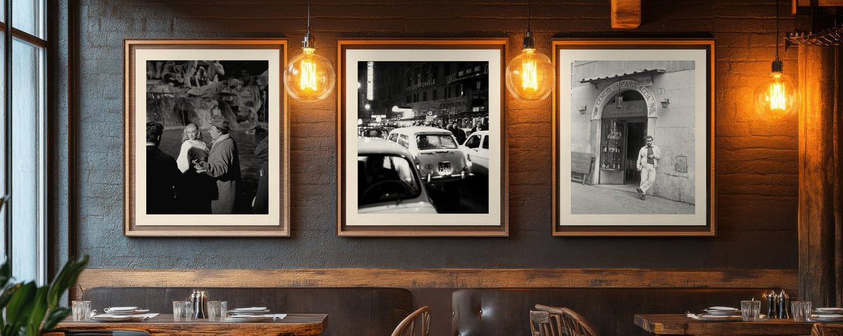 Three framed black-and-white photographs of the Dolce Vita era on a restaurant wall: Anita Ekberg and Marcello Mastroianni at the Trevi Fountain, Via Veneto at night, Lucio Dalla in Trastevere