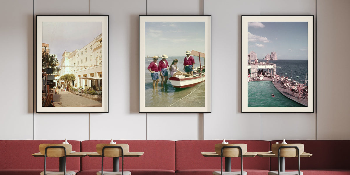 Three framed colour photographs from the 1960s on a restaurant wall: the Hotel Quisisana in Capri, Claudia Cardinale in a boat in Venice, the Canzone del Mare swimming pool with the Faraglioni