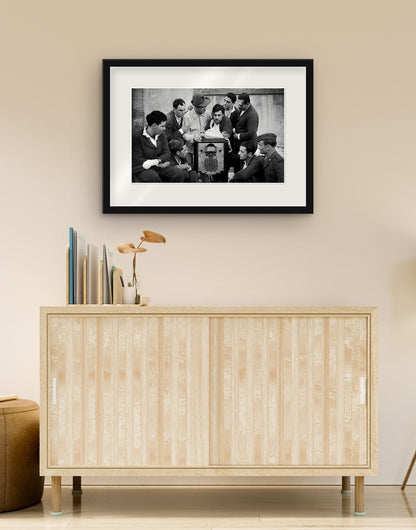 Fine art print of “Wounded soldiers listening to the radio, 1942” with black frame and mat, hanging in a living room above a sideboard
