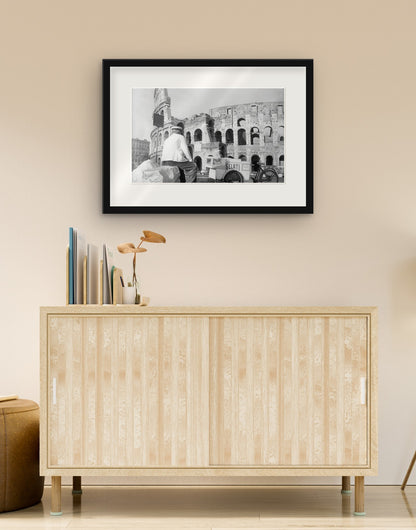 Stampa fine art di «Gelataio al Colosseo, Roma 1954» con cornice nera e passepartout, appesa in un soggiorno sopra una credenza