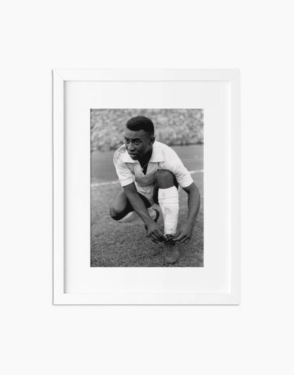 Pelè si allaccia le scarpe, Santos 1964 — stampa fine art con cornice bianca