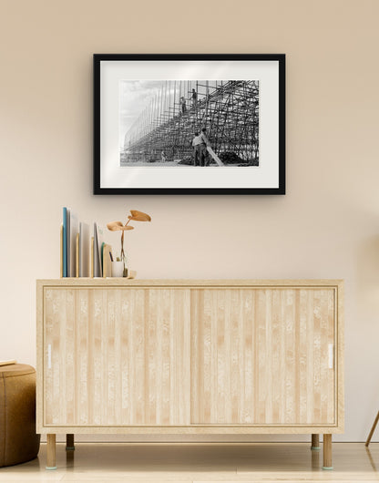Fine art print of “Building the Autostrada del Sole, 1958” with black frame and mat, hanging in a living room above a sideboard